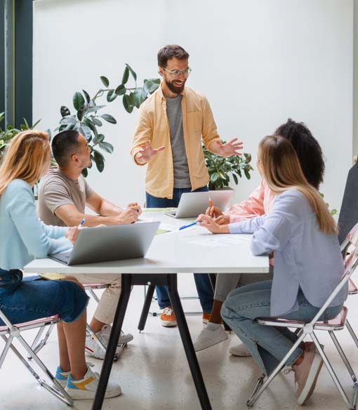 A team collaborating around a laptop-equipped table during a business meeting